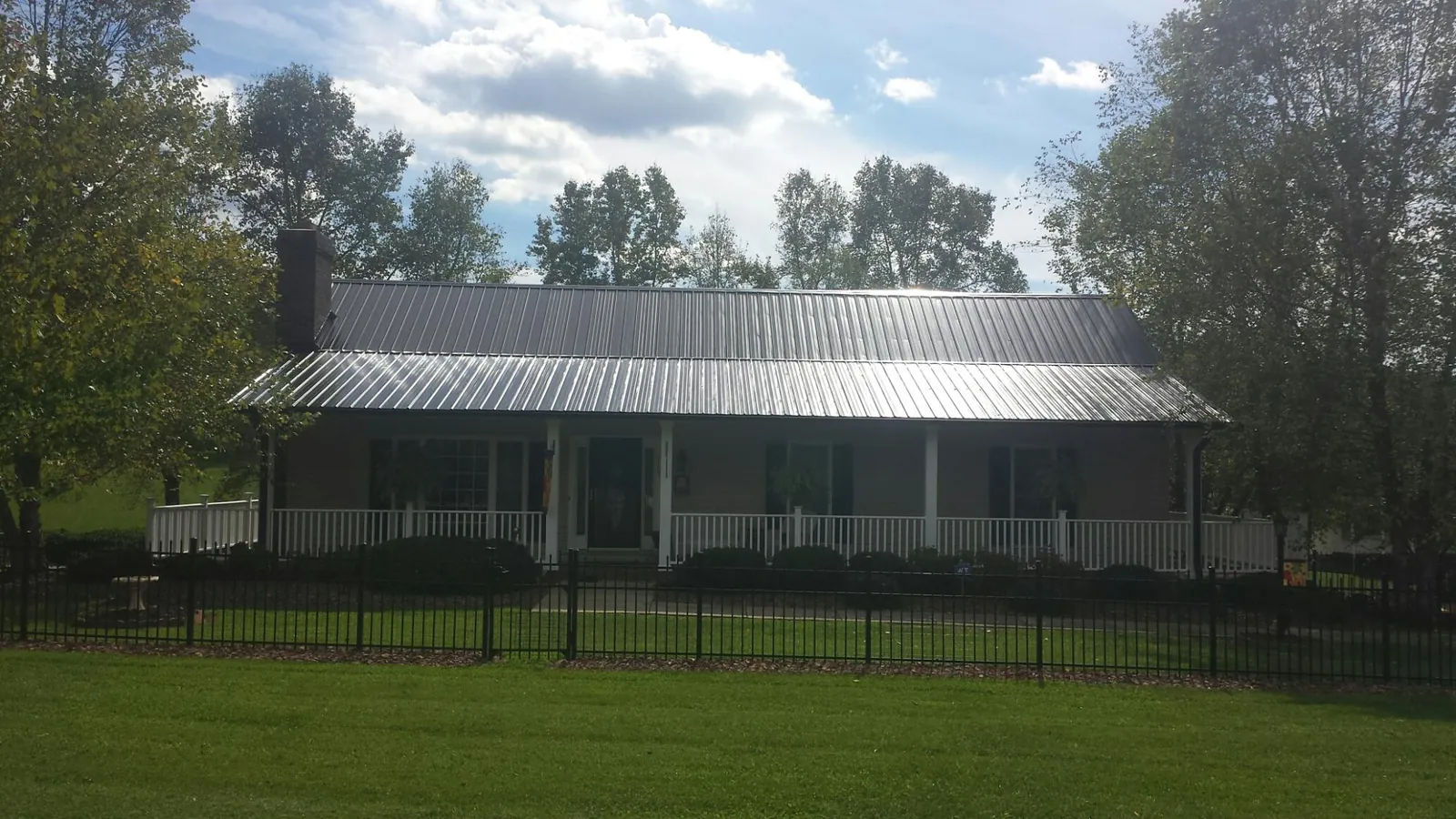 Gray metal roof on a brick ranch with a full width front porch — Gutter Guard Installation work by our crew in Dover